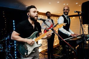 band with camera focused on the guitarist singing and playing