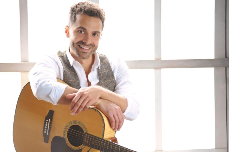 Singer sat down leaning on guitar